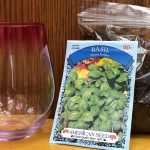 A photo of a plastic stemless wine glass, a packet of seeds, and a bag of soil.